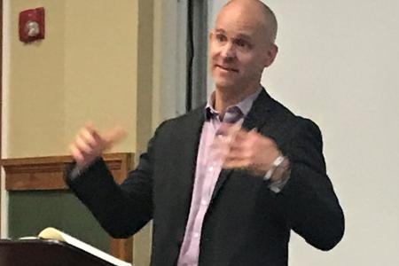Luke Dittrich gives lecture at podium in an MLC classroom