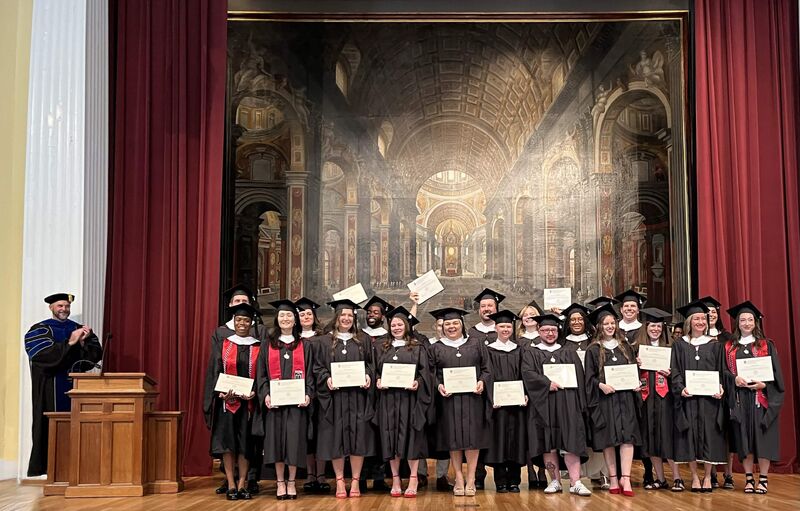 IOMP graduates standing on stage with their diplomas