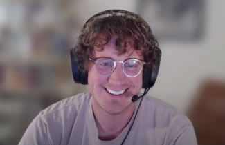 Photo of Alex Cole wearing a headset and glasses smiling