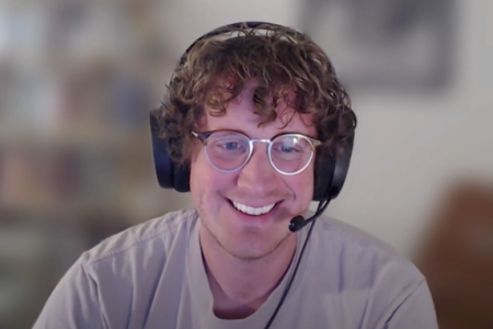 Photo of Alex Cole wearing a headset and glasses smiling